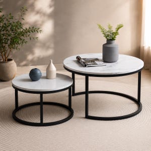 Peut inclure: Un ensemble de deux tables basses gigognes rondes avec des plateaux en faux marbre blanc et des cadres en métal noir. La plus petite table porte une sphère bleue et un vase crème, tandis que la plus grande présente un vase gris avec une plante verte.