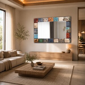 May include: A rectangular wall mirror featuring a frame constructed from an assortment of square tiles in various colors and textures, including shades of blue, orange, red, white, and metallic gold, mounted on a plain wall above a wooden console.