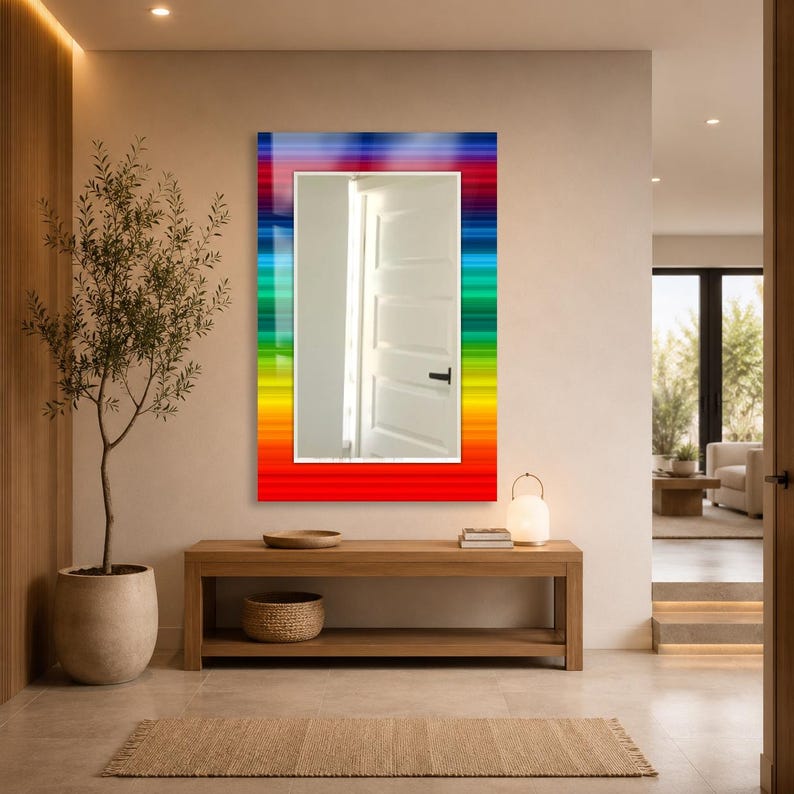 May include: A rectangular wall mirror featuring a vibrant, multi-colored border with horizontal stripes in shades of red, orange, yellow, green, blue, and purple. The central reflective glass surface shows a reflection of a white interior door.