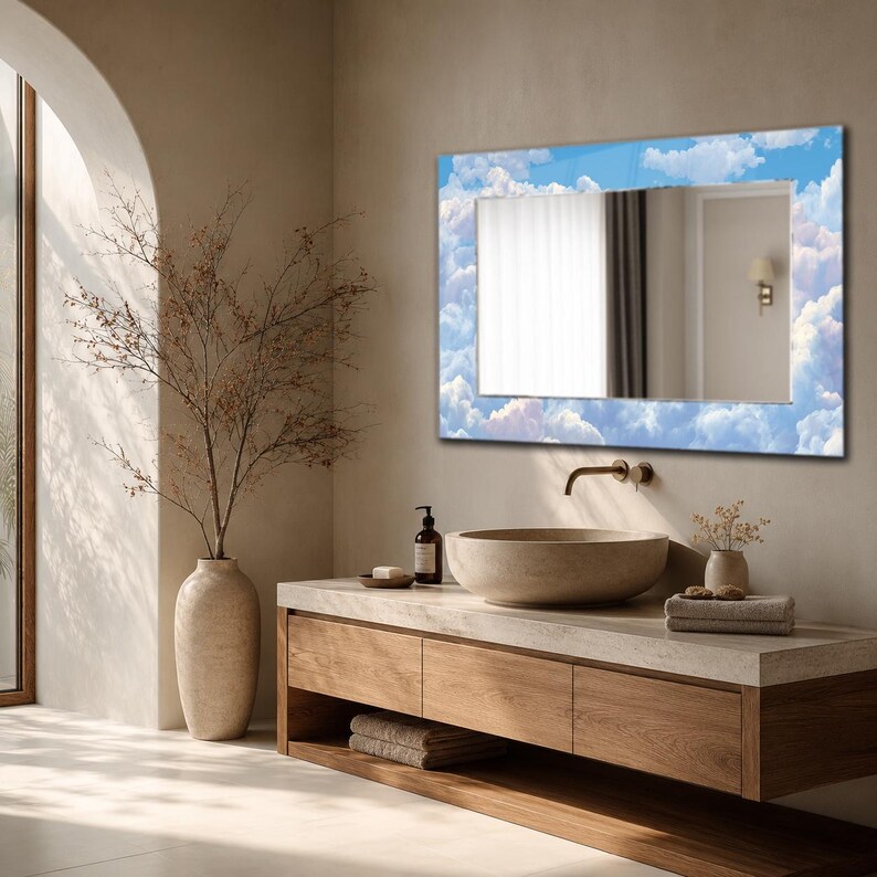 May include: A rectangular wall mirror featuring a decorative border printed with a blue sky and white clouds pattern. The mirror is mounted above a wooden vanity cabinet with a stone basin sink and a metal faucet, reflecting a room interior.
