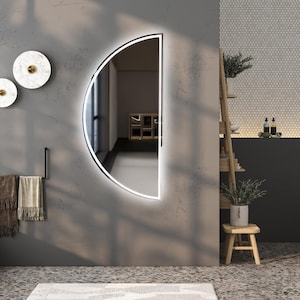May include: A semi-circular wall mirror featuring a sleek black frame and integrated LED backlighting that emits a soft glow. The mirror has a flat vertical edge and a curved outer edge, mounted on a gray wall surface in a bathroom setting.