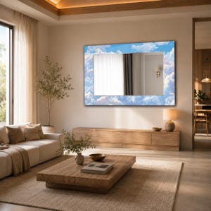 May include: A rectangular wall mirror featuring a decorative border printed with a blue sky and white clouds pattern. The central reflective glass surface provides a clear view of the room, reflecting a wall with a lamp and curtains.