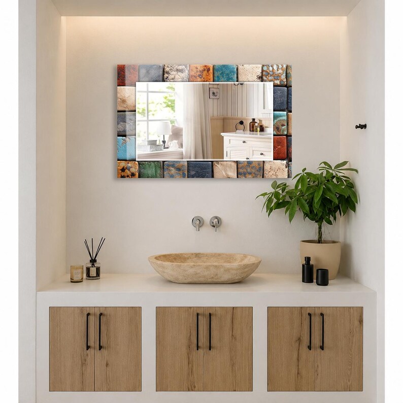 May include: A rectangular wall mirror featuring a frame composed of numerous small, square tiles in a variety of colors including blue, orange, white, brown, and gray. The mirror surface reflects a room with a window and a white cabinet.