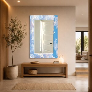 May include: A rectangular wall mirror featuring a decorative border printed with a bright blue sky and white fluffy clouds. The central reflective glass surface shows a clear reflection of a white interior door with a black handle.