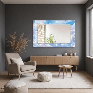 May include: A rectangular wall mirror featuring a decorative border printed with a bright blue sky and white clouds. The central reflective glass surface shows a reflection of a window with blinds and a green plant, framed by the sky-themed border.