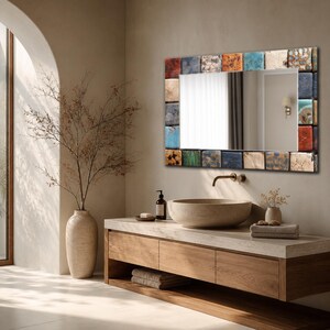 May include: A rectangular wall mirror featuring a decorative frame composed of small, square, multi-colored ceramic tiles in shades of blue, orange, green, and cream. The mirror has a reflective glass center and is mounted on a neutral-toned wall.