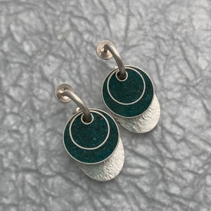 May include: A pair of silver earrings with a turquoise stone and a textured silver disc.