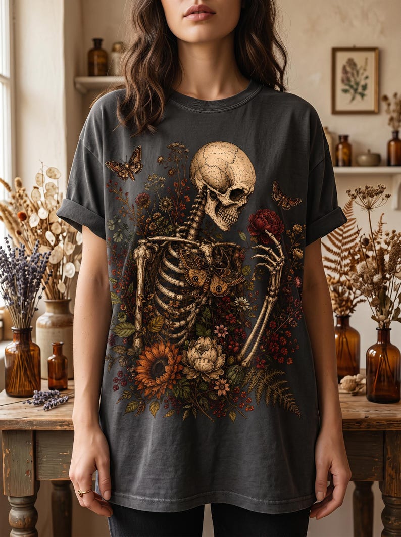 A person wearing a dark grey oversized T-shirt with a detailed illustration of a floral skeleton graphic on the front.