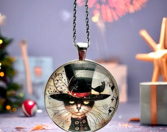 May include: A silver-toned pendant necklace featuring a round glass charm with a cat wearing a top hat. The cat has yellow eyes and is dressed in a black coat. The charm has a black cat silhouette and decorative swirls. The background is blurred.