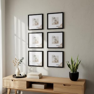 Puede incluir: Un conjunto de seis marcos de fotos cuadrados de color negro dispuestos en dos columnas verticales sobre una pared. Cada marco contiene un paspartú blanco y una imagen de muestra con el texto PHOTO FRAME. Los marcos se sitúan sobre una mesa consola de madera clara.