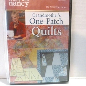 May include: A DVD titled Sewing with Nancy: Grandmother's One-Patch Quilts by Nancy Zieman. The cover features a photo of Nancy Zieman, a pink and orange mottled background, and a blue and white patterned quilt block with sewing templates.