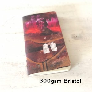 May include: A small, red, brown, and white notebook with a colorful abstract design. The notebook is made of 300gsm Bristol paper.