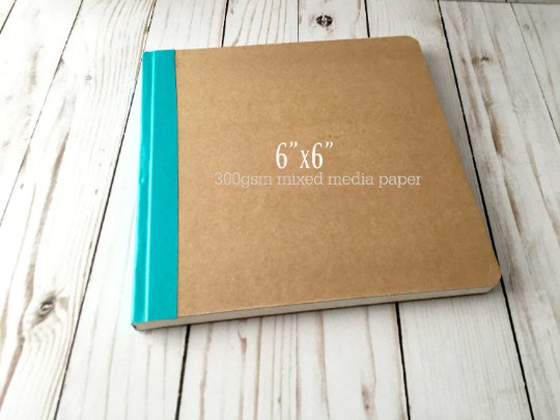 Puede incluir: Un cuaderno de bocetos marr&oacute;n con una encuadernaci&oacute;n turquesa. La portada tiene el texto "6" x "6" 300 g/m&sup2; papel mixto" impreso.