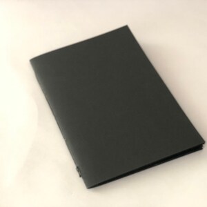 May include: A black, rectangular notebook with a smooth, matte finish.
