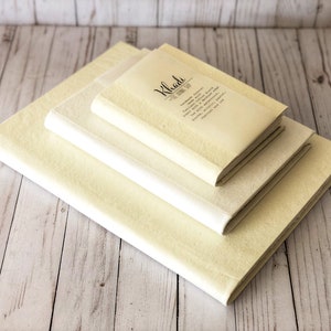 May include: Three cream-colored notebooks stacked on top of each other. The top notebook has the text "Khaki The Journal Joy" printed on the cover.