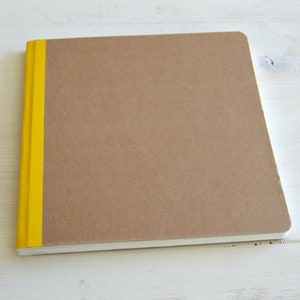 Puede incluir: Un cuaderno marr&oacute;n con una franja amarilla en el lomo.