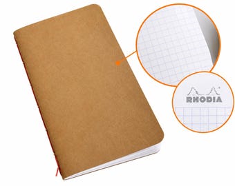 May include: A rectangular notebook with a plain tan cover and red stitched binding along the spine. Two circular insets show white interior pages with a blue grid pattern and the Rhodia logo featuring two pine trees above the brand name.