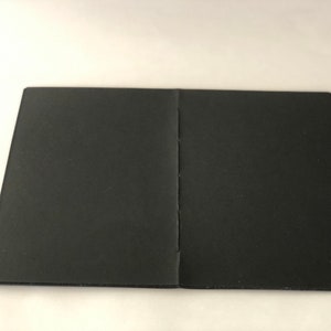 May include: A black, closed notebook with a sewn binding.