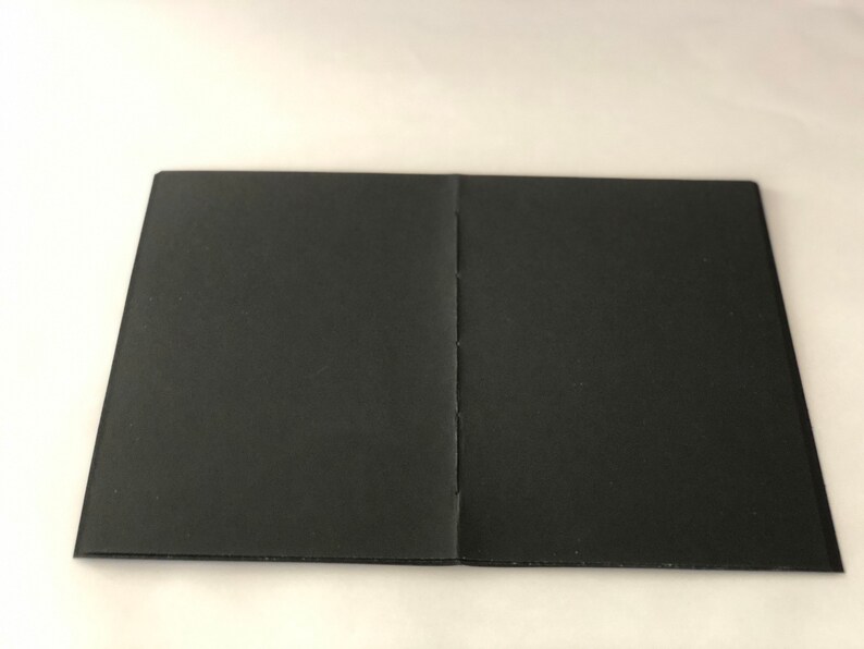May include: A black, closed notebook with a sewn binding.