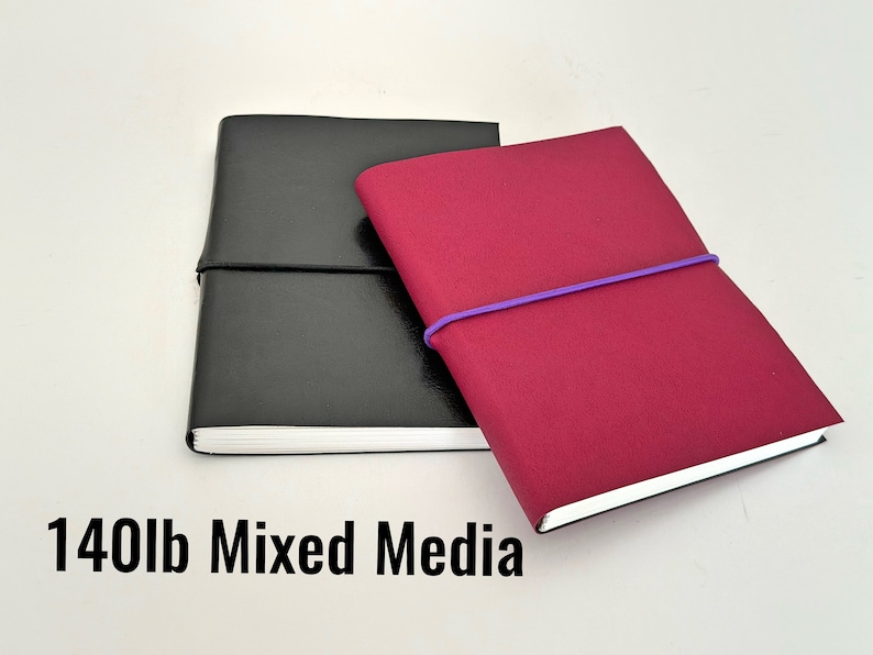 May include: Two bound journals, one black and one burgundy, with elastic bands. The black journal has a white label that reads "140lb Mixed Media".