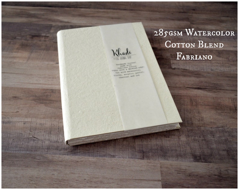 May include: A white watercolor sketchbook with a textured cover. The cover has the text "Khadi" and "285gsm Watercolor Cotton Blend Fabriano" printed on it.