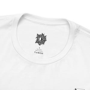 Puede incluir: Una camiseta blanca con una etiqueta impresa en negro en el interior del cuello. La etiqueta muestra el texto MOON LIGHT, la talla L, 100% Cotton, Made in Honduras y una serie de cinco símbolos de cuidado de ropa en una fila horizontal.