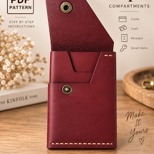 Può includere: Un portafoglio in pelle rosso scuro con una patta dotata di chiusura a scatto in ottone, una tasca aperta e cuciture visibili lungo il bordo inferiore. L'immagine include testo che indica un modello PDF con 4 scomparti per carte, contanti, ricevute e piccoli oggetti.