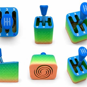 May include: A multi-coloured gear shifter desk accessory featuring a blue top plate with white numbers 1, 2, 3, 4, 5 and R. The base transitions from green to orange with a diamond texture, and the bottom features a spiral pattern design.