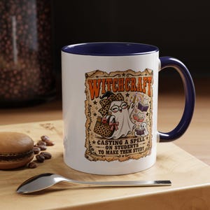 May include: A white ceramic mug with a dark blue interior and handle. The front features a graphic of a ghost wearing a leopard print bow and glasses, holding a wand and bag. Text reads: WITCHCRAFT CASTING A SPELL ON STUDENTS TO MAKE THEM STUDY.