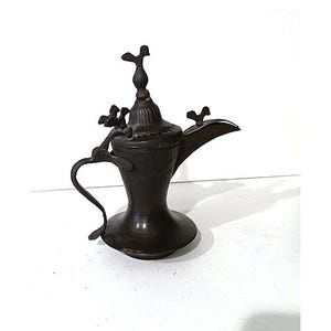 May include: A dark brown metal coffee pot with a wide base, a curved handle, and a long, tapered spout. The lid features a decorative finial and small bird-shaped ornaments attached to the top and the handle area, creating a distinct silhouette.