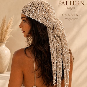 Peut inclure: Un foulard en crochet beige avec une texture en maille ouverte ornée de petites paillettes argentées réfléchissantes. Le foulard est noué à l'arrière avec de longues extrémités tombantes. Le texte indique : CROCHET PATTERN YASSINE.