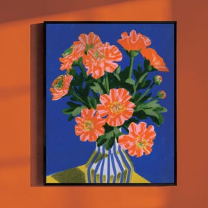 May include: A framed art print featuring a bouquet of vibrant orange flowers with green leaves in a blue and white striped vase. The flowers are set against a solid deep blue background, with a yellow surface visible beneath the vase.