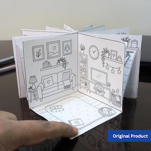 以下が含まれることがあります： リビングルームのインテリアを描いた白黒の線画の紙製アコーディオンブック。ソファ、テレビ、本棚、掛け時計、スリッパが置かれたラグなどが描かれており、立体的に広げることができる構造になっています。