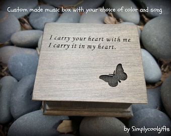 May include: A wooden music box with a butterfly design and the inscription "I carry your heart with me I carry it in my heart." The box is made to order and can be customized with a choice of color and song.