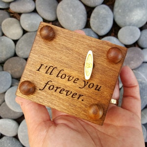 Pu&ograve; includere: Una scatola di musica in legno con una manovella in cima. La scatola &egrave; incisa con le parole "I'll love you forever."