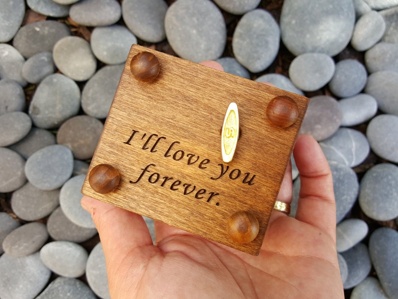 Pu&ograve; includere: Una scatola di musica in legno con una manovella in cima. La scatola &egrave; incisa con le parole "I'll love you forever."
