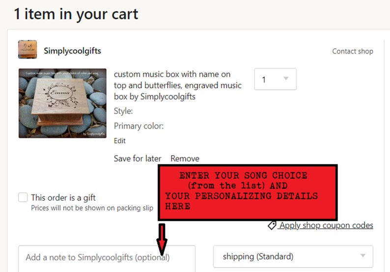Pu&ograve; includere: Una scatola di musica in legno con un design a farfalla e il nome "Emma" inciso sul coperchio. La scatola &egrave; mostrata su un letto di piccole pietre rotonde. Il testo "ENTER YOUR SONG CHOICE (from the list) AND YOUR PERSONALIZING DETAILS HERE" &egrave; visualizzato in rosso.