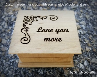 May include: A wooden music box with a custom engraved message that reads "Love you more". The box has a decorative floral design in the corner.