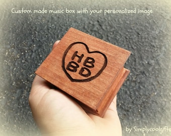 May include: A small wooden music box with a heart-shaped design engraved with the letters "HBD".
