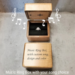 May include: A wooden music box with a ring inside. The box is engraved with the text "Music Ring Box with custom song, design and color".