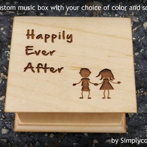 Pode incluir: Uma caixa de m&uacute;sica de madeira com as palavras "Happily Ever After" gravadas na parte superior. Duas figuras de pau est&atilde;o de m&atilde;os dadas abaixo do texto. A caixa de m&uacute;sica &eacute; feita por Simplycoolgifts.
