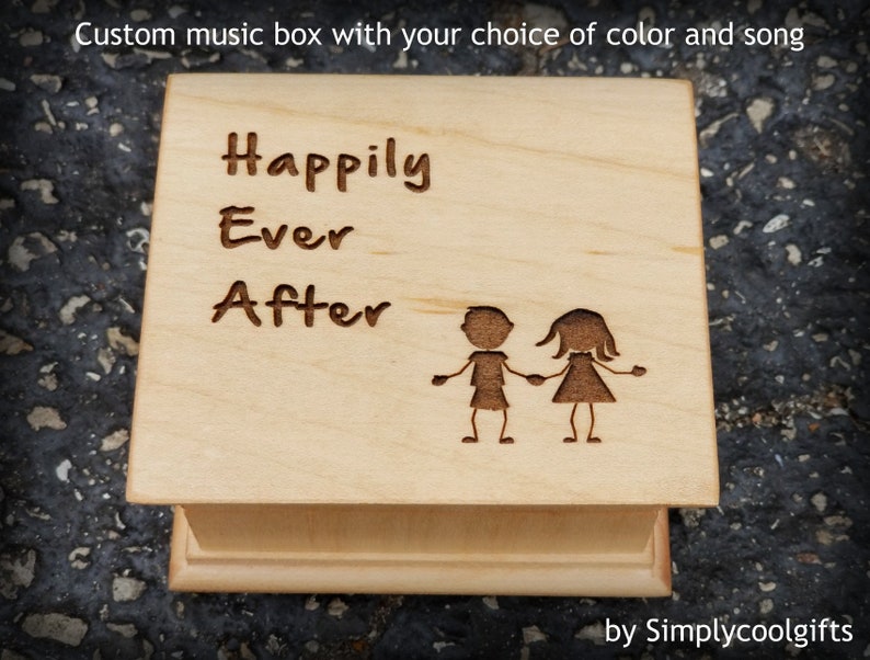 Pode incluir: Uma caixa de m&uacute;sica de madeira com as palavras "Happily Ever After" gravadas na parte superior. Duas figuras de pau est&atilde;o de m&atilde;os dadas abaixo do texto. A caixa de m&uacute;sica &eacute; feita por Simplycoolgifts.