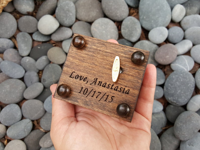 Pu&ograve; includere: Una scatola musicale in legno con una manovella dorata e un'iscrizione personalizzata che recita "Love, Anastasia 10/17/15".