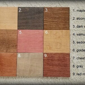 Pu&ograve; includere: Nove campioni di tinta per legno etichettati con i numeri da 1 a 9. I campioni sono disposti in tre file di tre. La prima fila mostra acero, ebano e noce scuro. La seconda fila mostra noce, rosso sedona e quercia dorata. La terza fila mostra castagno, grigio e mogano rosso.