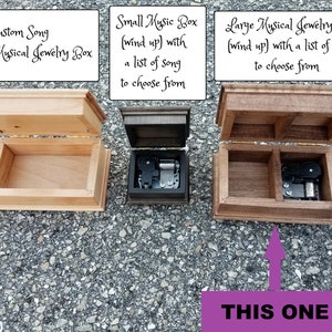 Puede incluir: Tres cajas de m&uacute;sica de madera con las tapas abiertas. La caja de la izquierda est&aacute; etiquetada como "Custom Song Digital Musical Jewelry Box". La caja del medio est&aacute; etiquetada como "Small Music Box (wind up) with a list of song to choose from". La caja de la derecha est&aacute; etiquetada como "Large Musical Jewelry Box (wind up) with a list of songs to choose from". Una flecha apunta a la caja m&aacute;s a la derecha con el texto "THIS ONE" debajo.