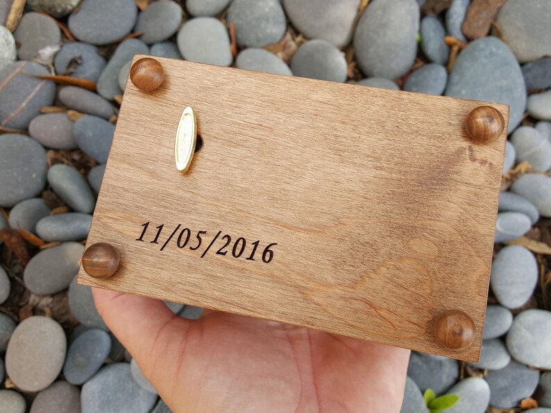 Puede incluir: Una caja de m&uacute;sica de madera con una llave de cuerda de lat&oacute;n y una fecha grabada en la parte superior: 11/05/2016.