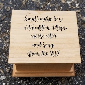 May include: A small wooden music box with the text "Small music box with custom design. Choose color and song from the list" engraved on the top.