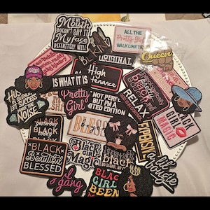 May include: A collection of embroidered fabric patches featuring various motivational and expressive phrases in black, pink, white, and gold thread. The patches include illustrations of faces, lips, and crowns, with text such as Black Girl Magic, Pretty Girl, and High Maintenance.