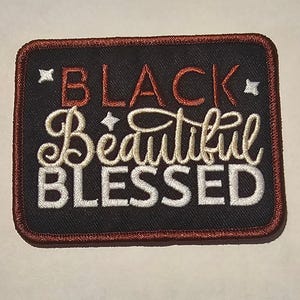 May include: A rectangular embroidered patch with a black background and a dark red border. The text reads BLACK in red, Beautiful in cream cursive, and BLESSED in white block letters, accented by four small white four-pointed star icons.