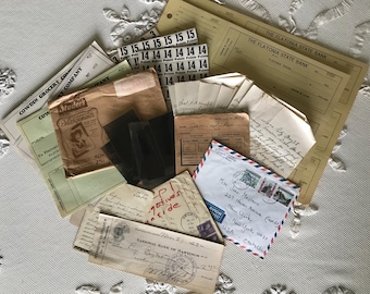 May include: A collection of vintage ephemera, including a brown envelope with a handwritten address, a stack of old letters, a few black and white photographs, and a few pieces of paper with handwritten notes.